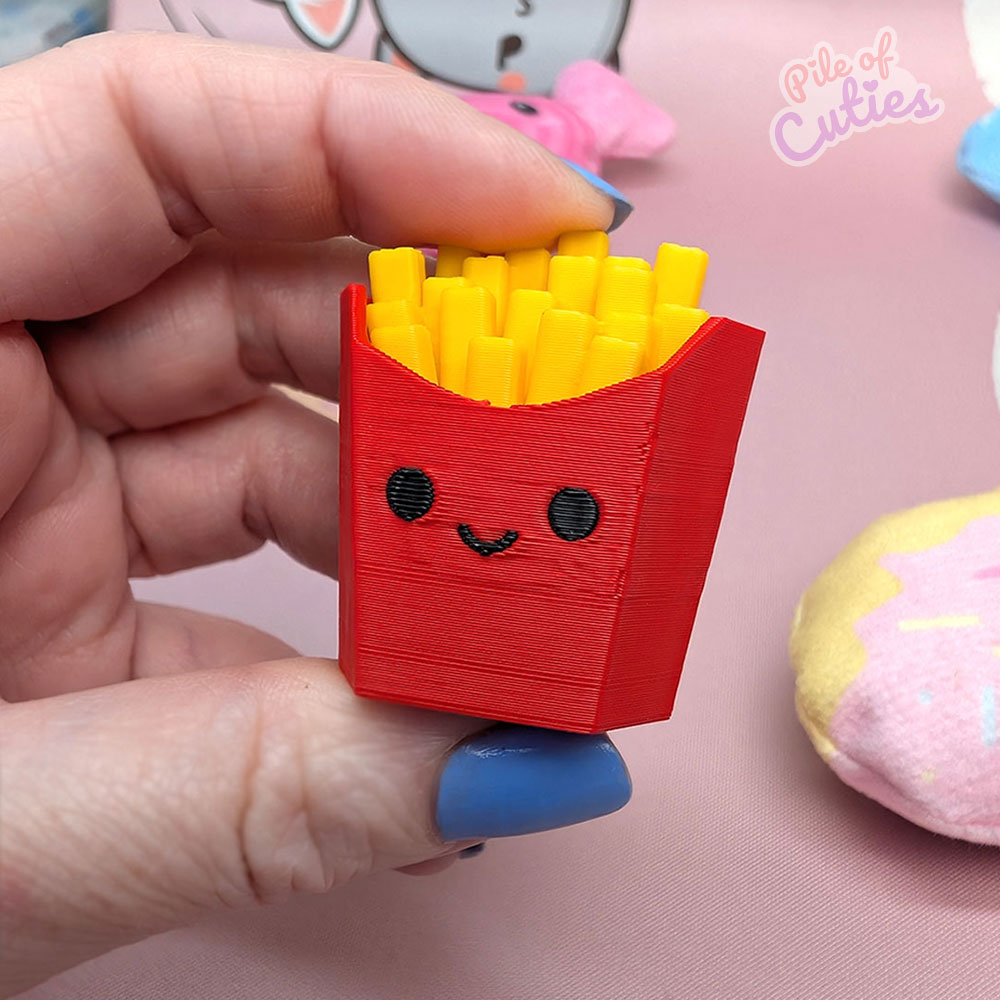 French fry shaped clicker keychain held in hand showing size